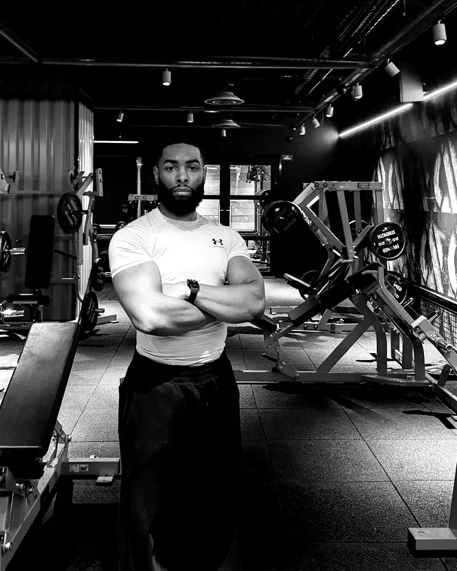 Portrait de Nathanaël, bras croisés, dans une salle de musculation